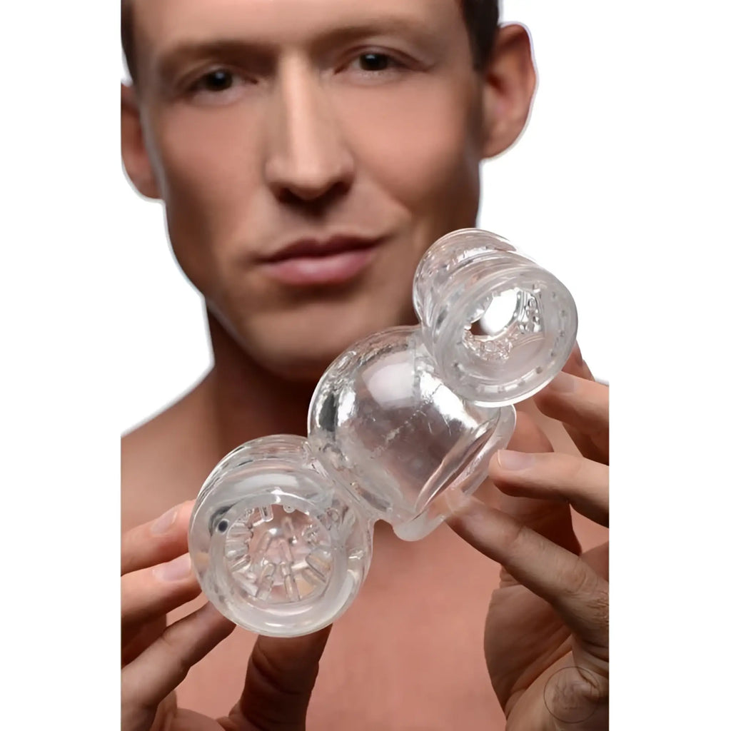 A man holds a clear, textured, double-ended Wand Essentials Twin Turbo Stroker wand attachment for men.