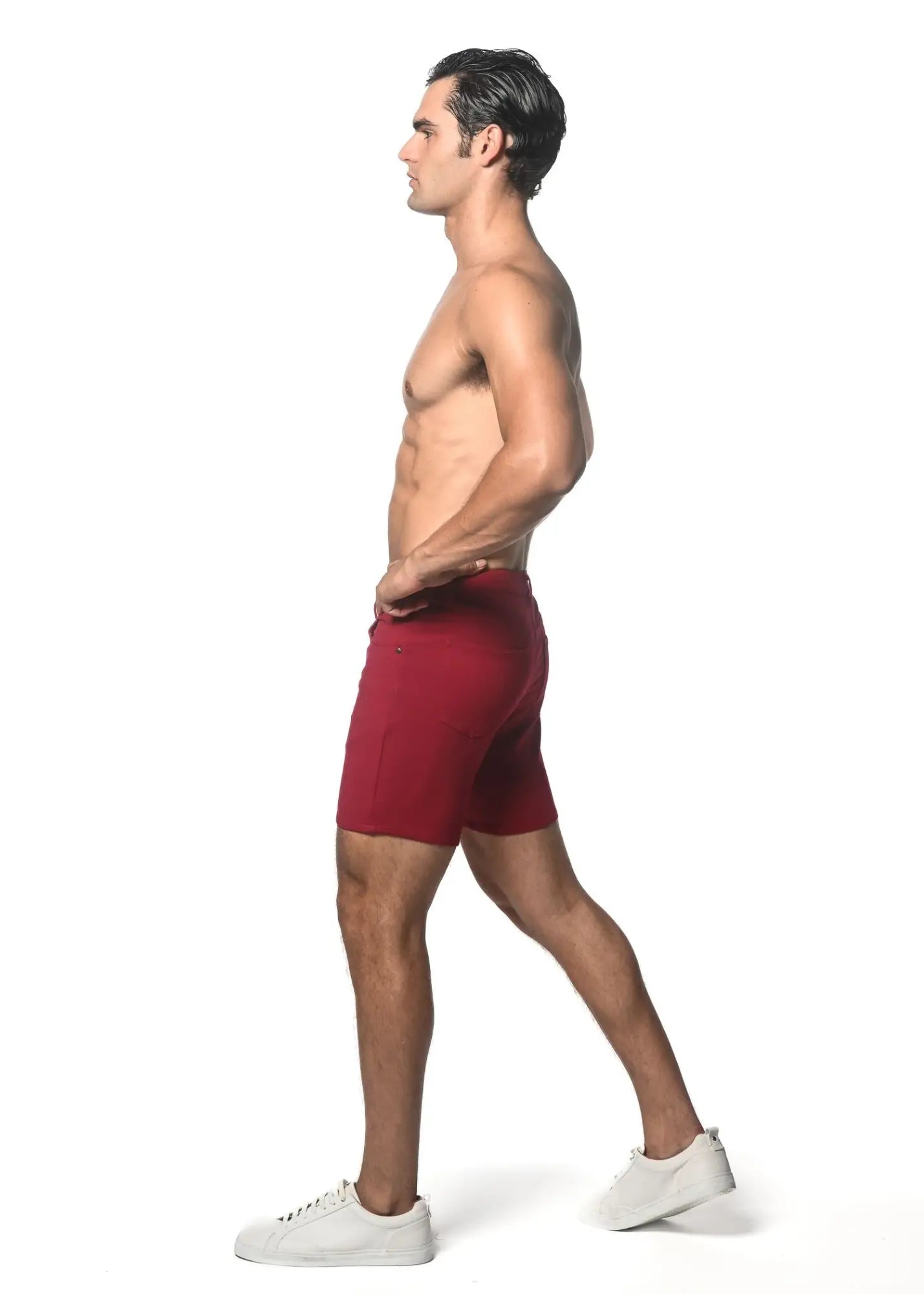 A pair of deep red washed denim stretch knit athletic shorts worn by a model showcasing a form-fitting design