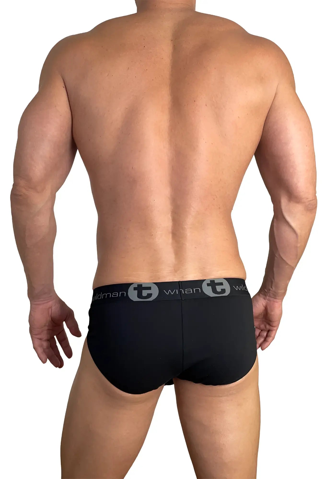 Back view of a muscular man wearing black WildmanT cotton briefs with a branded grey logo waistband.