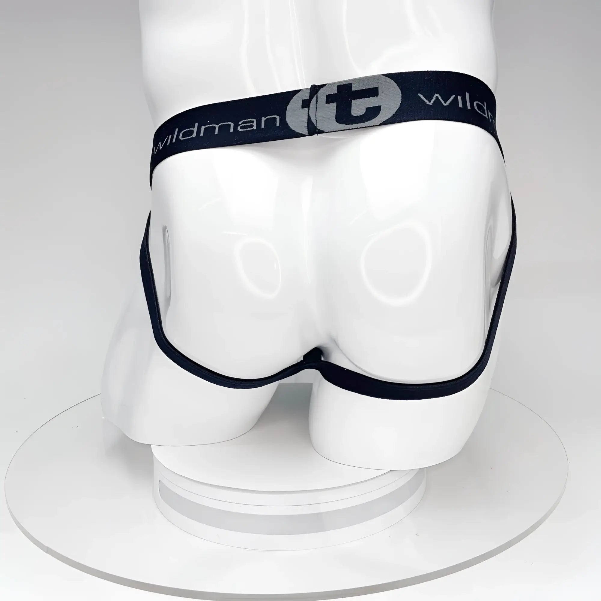 Back view of a black WildmanT jockstrap on a white mannequin torso, featuring a branded elastic waistband with logo.