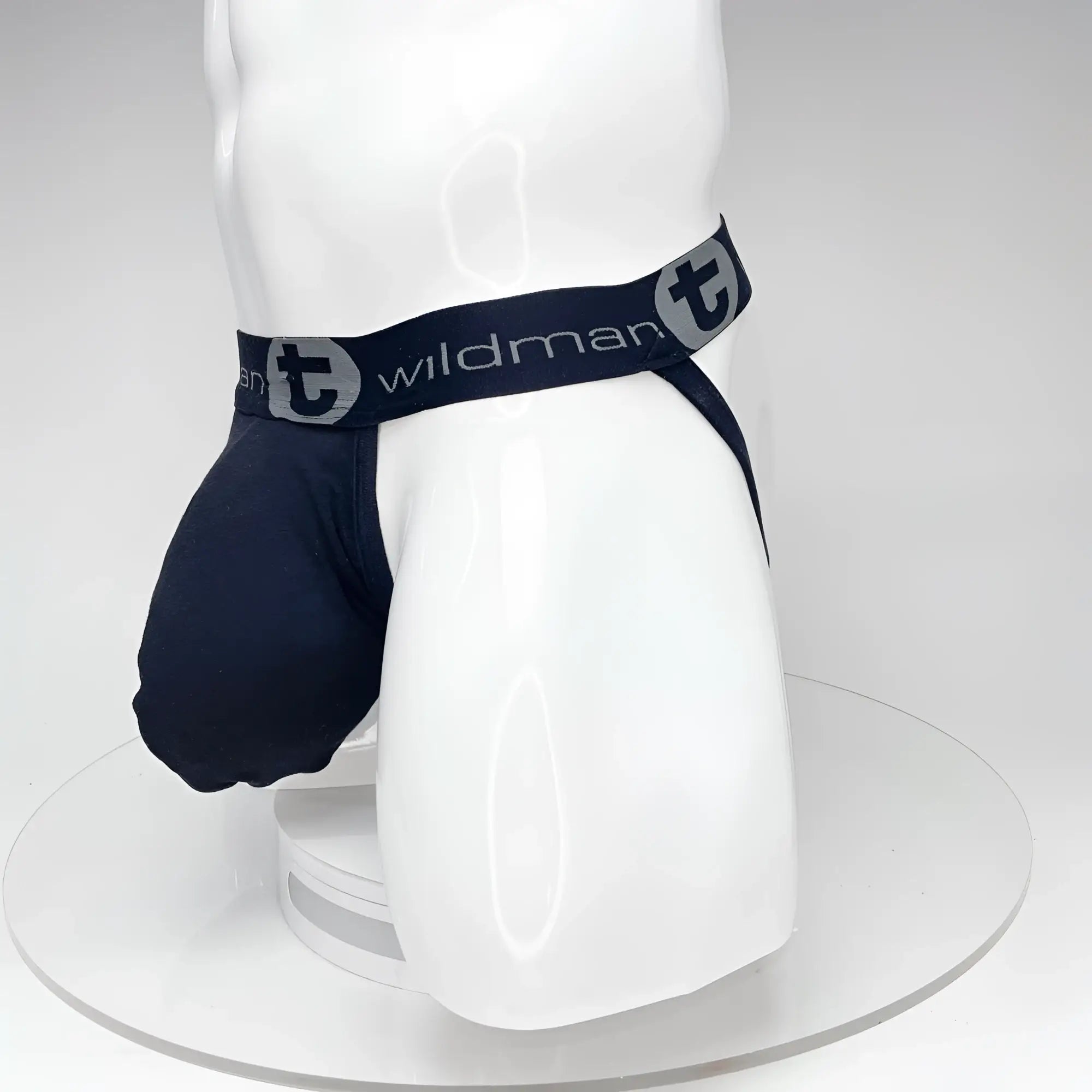 Black WildmanT jockstrap with a large front pouch and a branded elastic waistband on a white mannequin torso.