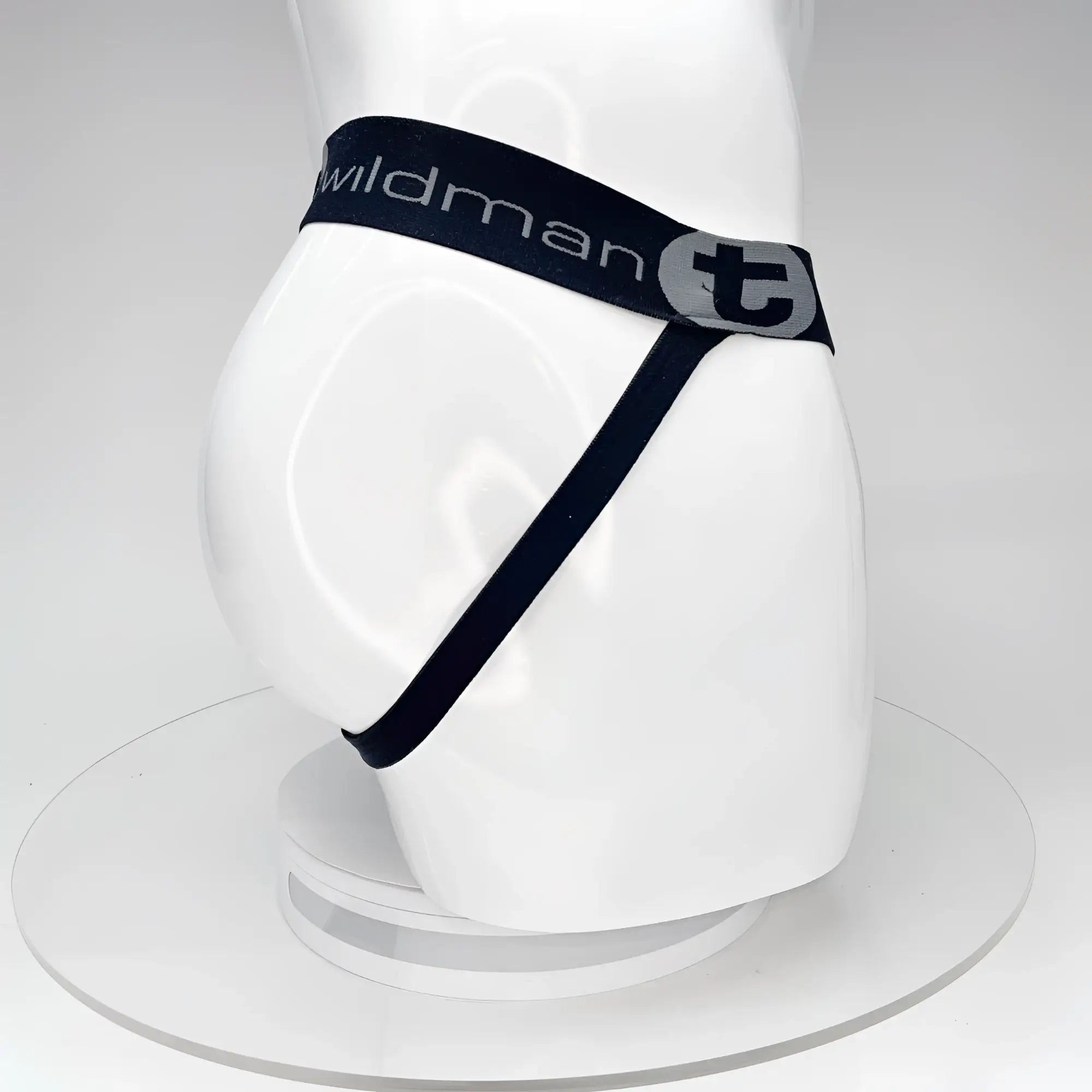 Black WildmanT jockstrap on a white mannequin, featuring a branded elastic waistband with a "T" logo and thin strap.