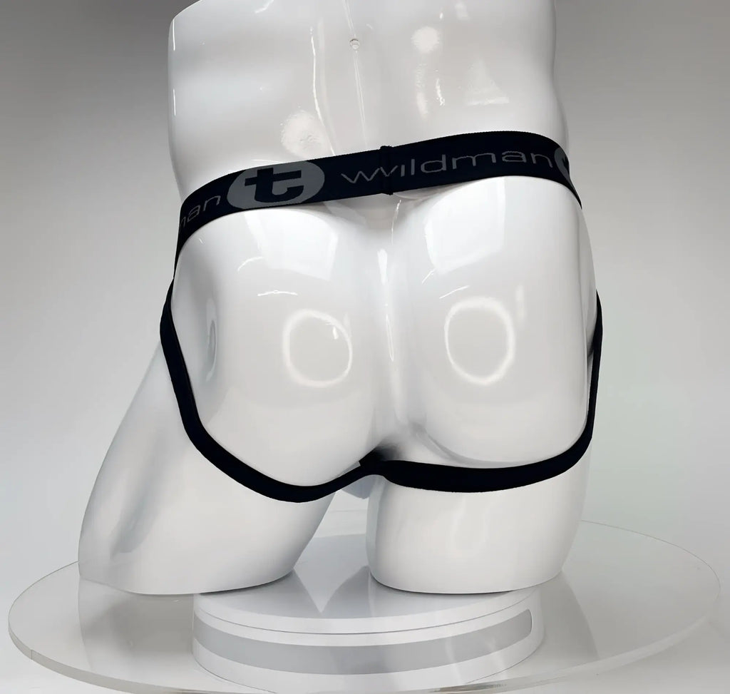 White WildmanT jockstrap on a white mannequin, featuring a black waistband with "WildmanT" logo and black leg straps.