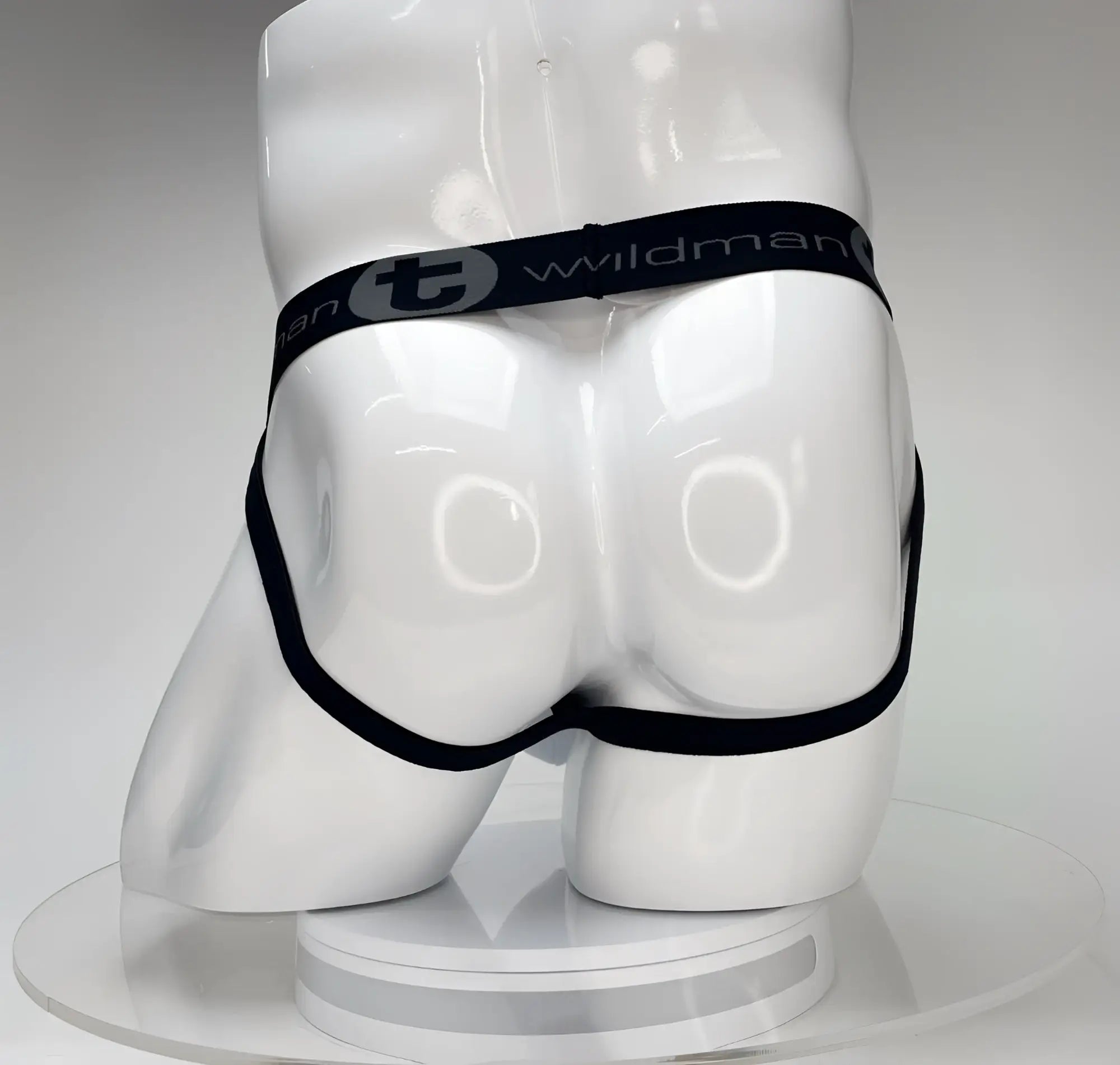 White WildmanT jockstrap on a white mannequin, featuring a black waistband with "WildmanT" logo and black leg straps.