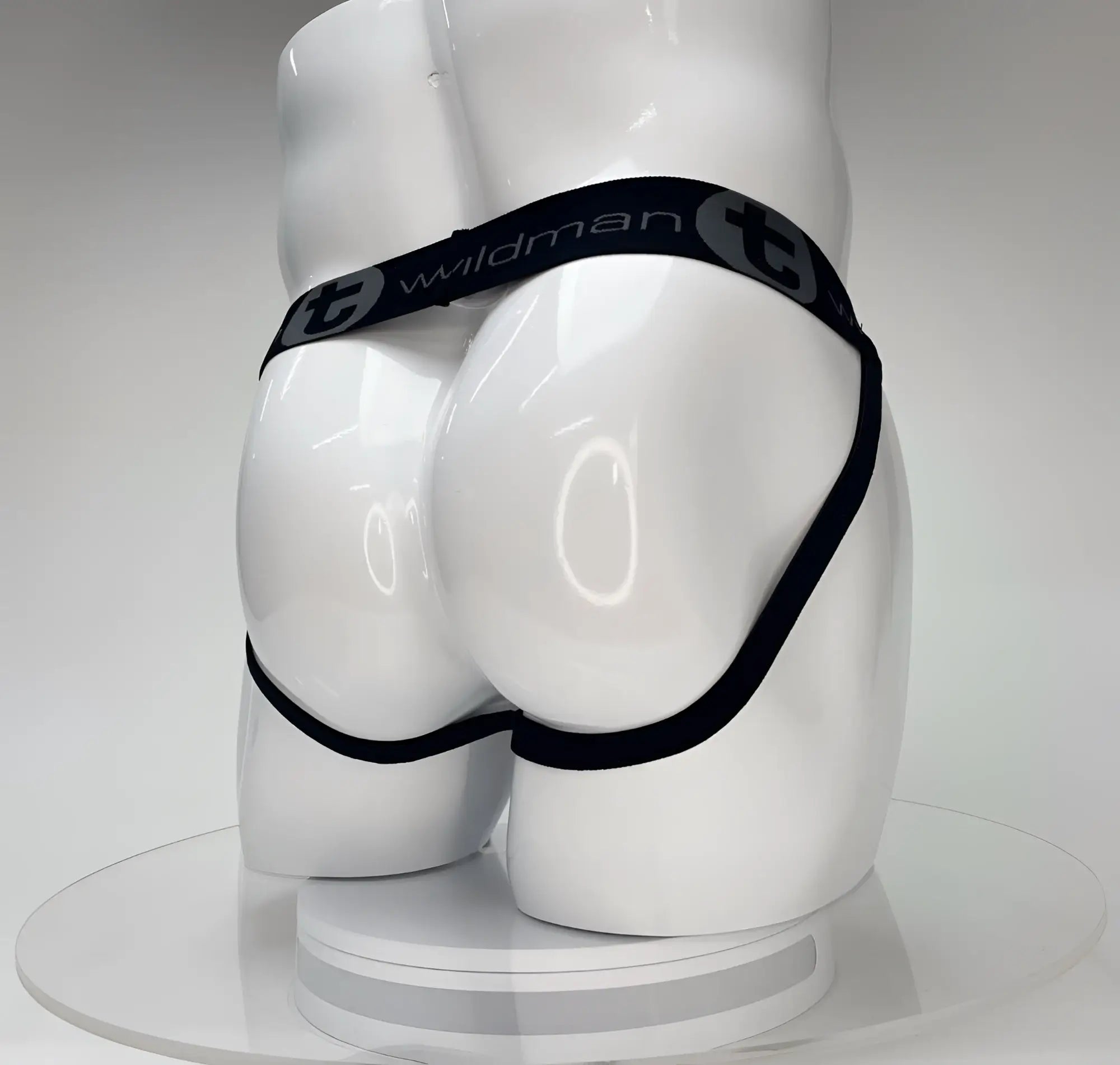 White jockstrap on a glossy mannequin torso, featuring a black waistband with the "WildmanT" logo.