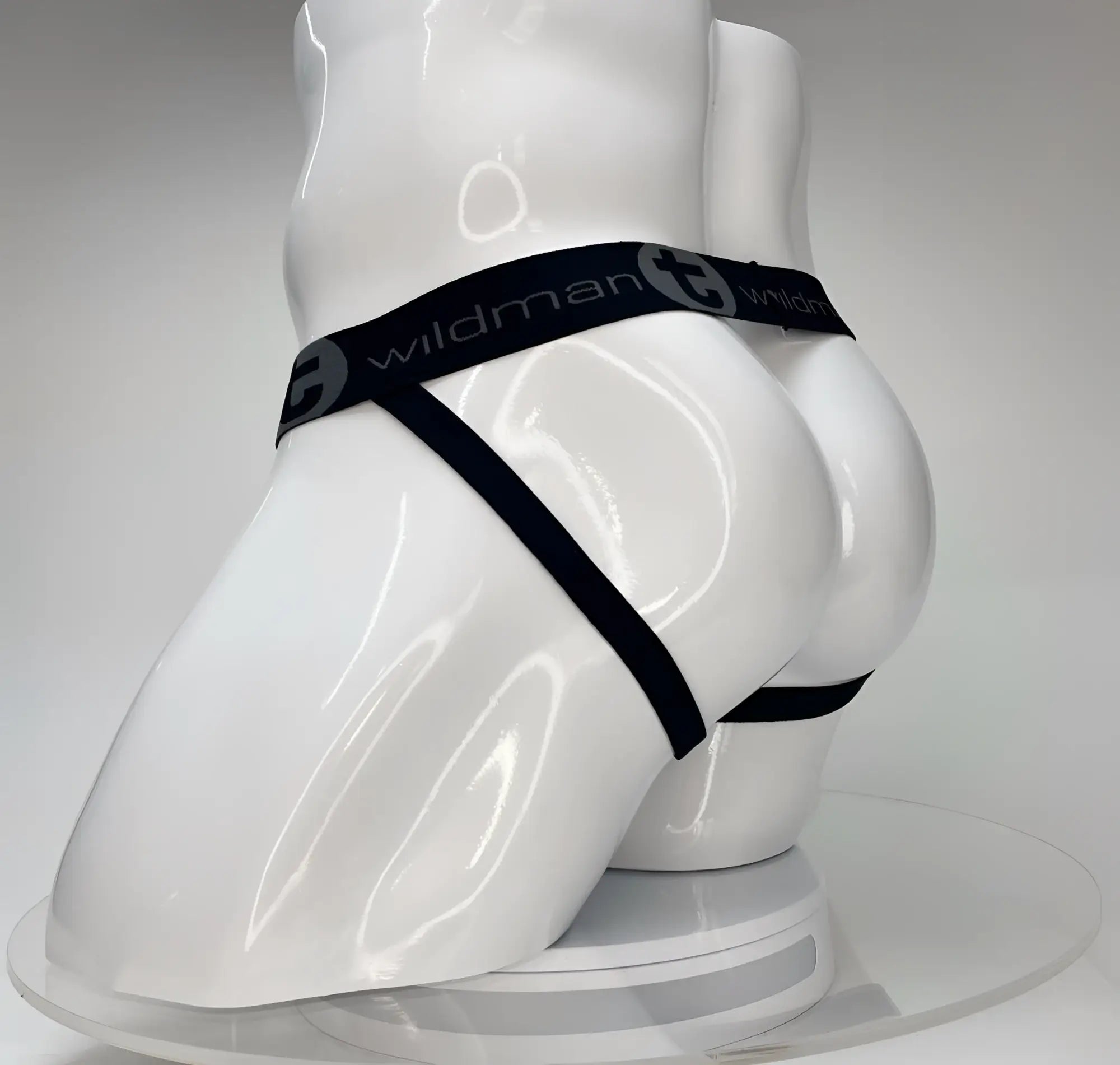 White WildmanT jockstrap on a mannequin featuring a black branded elastic waistband and thin leg straps.