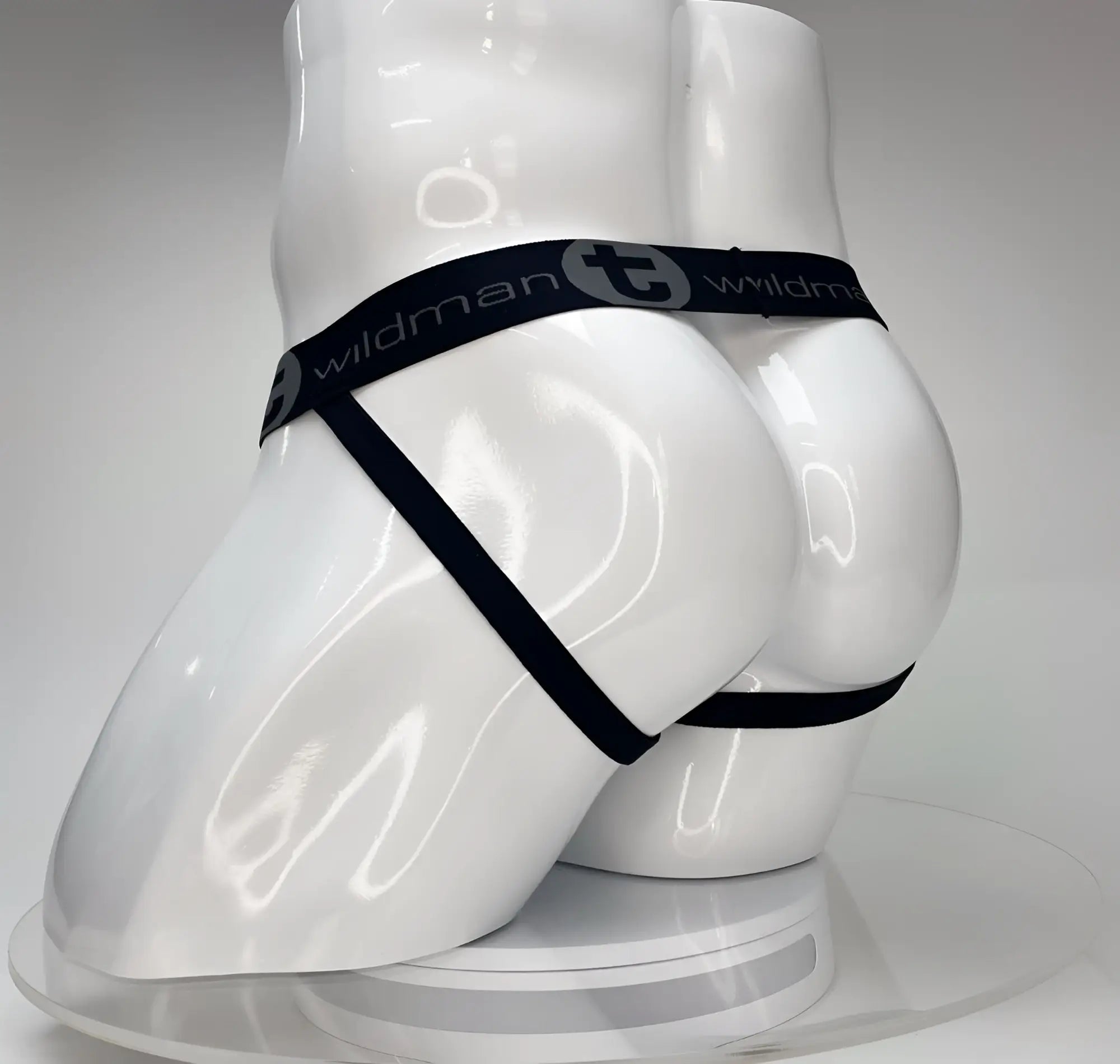 White jockstrap on a white mannequin torso, featuring a black waistband with the "WildmanT" logo in gray.
