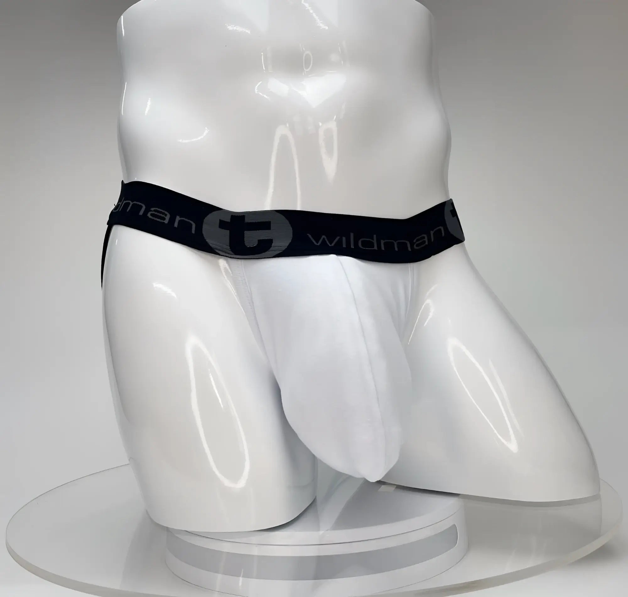 White WildmanT jockstrap with a large front pouch and a black branded elastic waistband on a white mannequin torso.