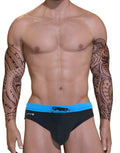 Muscular man with tribal arm tattoos wearing a black swim bikini with a blue waistband and front drawstring.