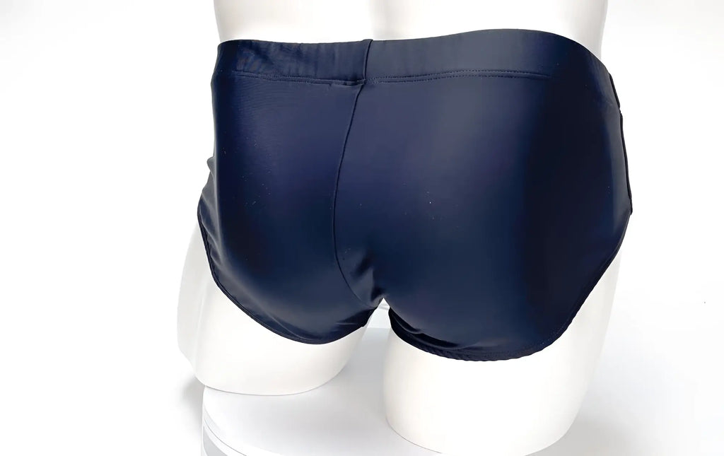 Back view of a plain black WildmanT Big Boy Pouch swim brief on a mannequin against a white background.