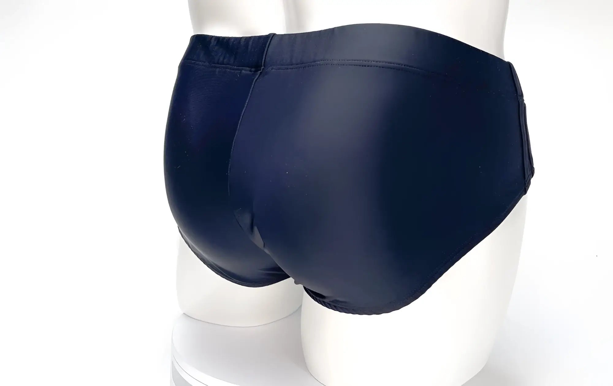 Back view of a solid black WildmanT Big Boy Pouch swim brief on a white mannequin.