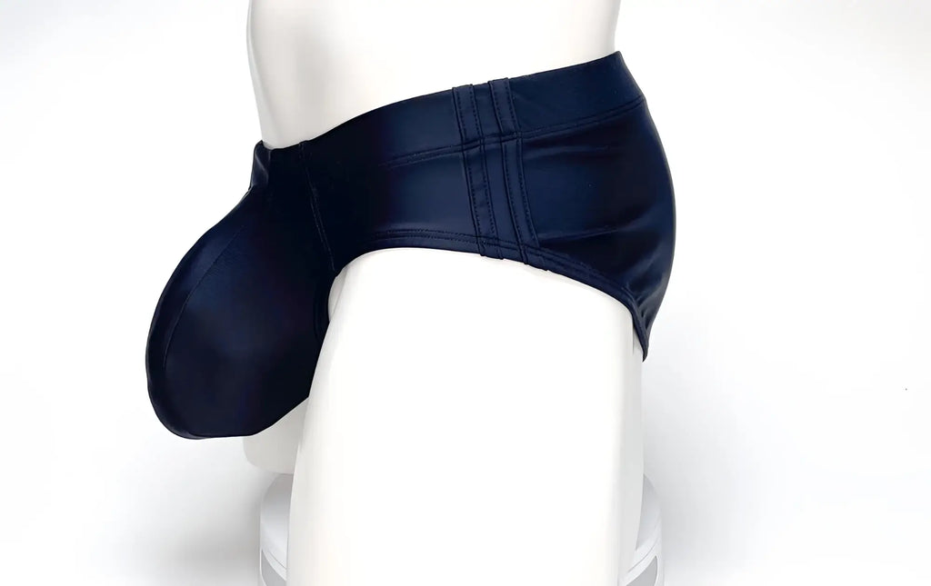 Side profile of a WildmanT black swim brief featuring a prominent, contoured pouch on a white mannequin.