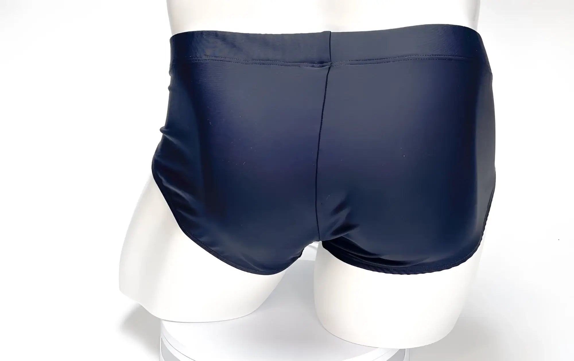 Rear view of a black WildmanT Big Boy Pouch swim brief on a white mannequin.