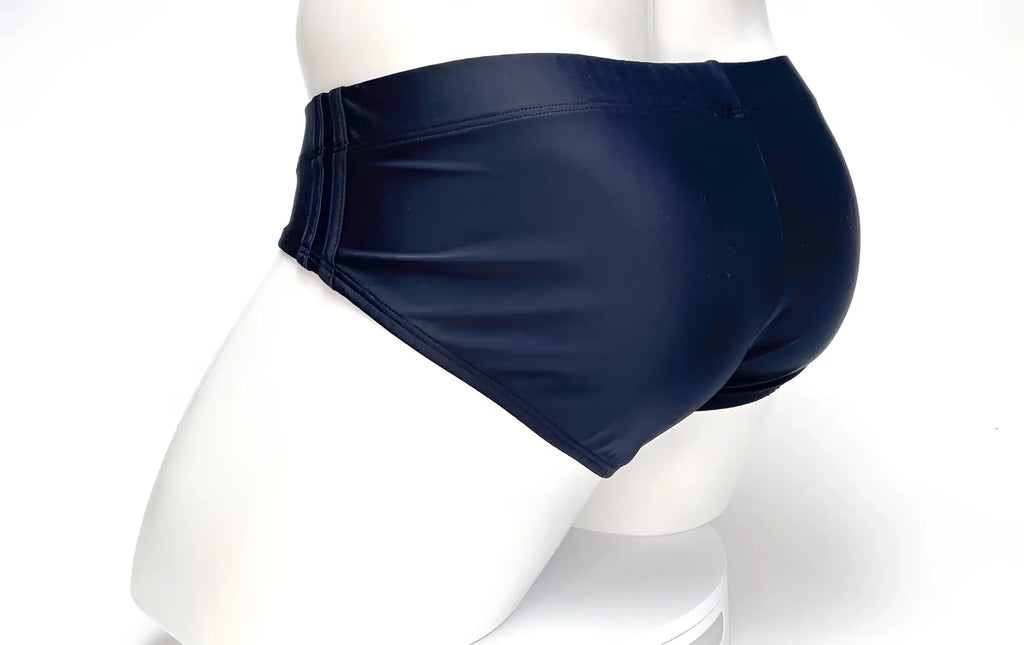 Black WildmanT swim brief seen from behind on a mannequin, featuring a smooth, form-fitting design with side stitching.