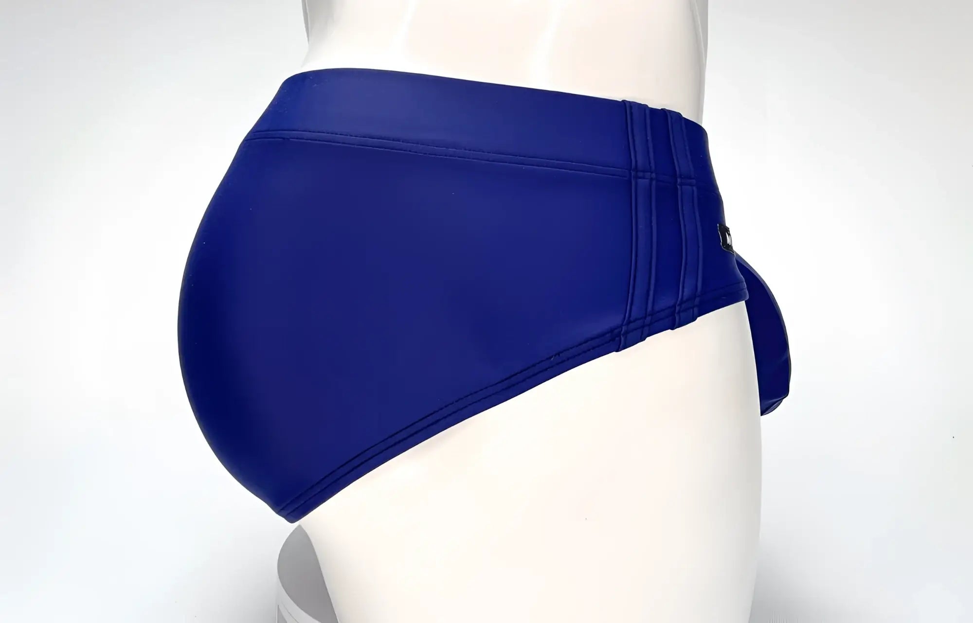 Side view of a navy blue WildmanT Big Boy pouch swim brief on a mannequin, featuring reinforced side stitching.