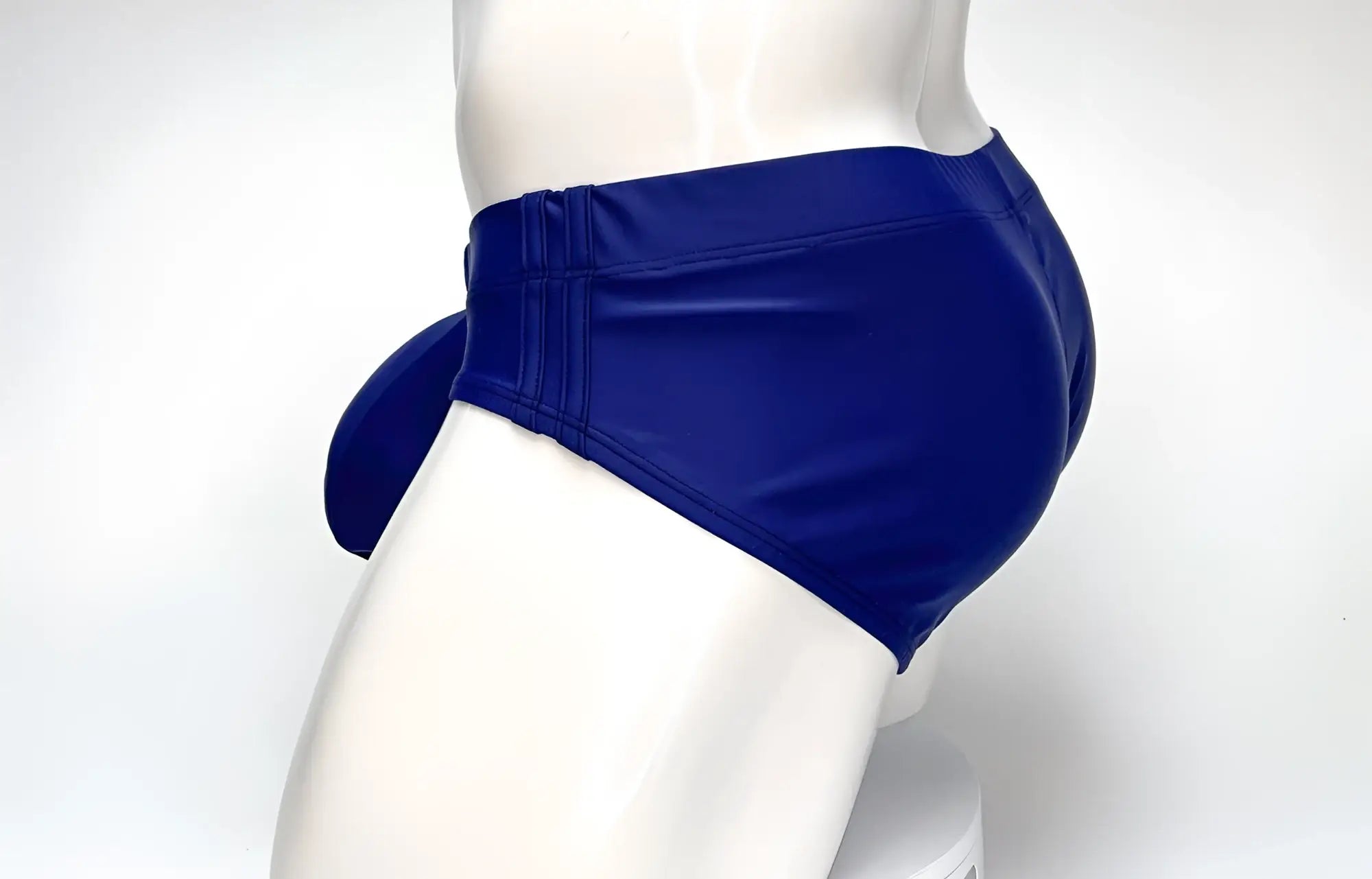 Side view of a navy blue WildmanT Big Boy pouch swim brief on a white mannequin.