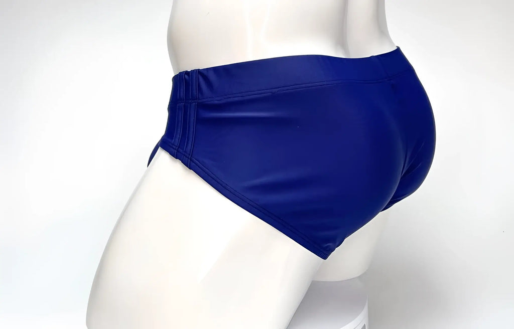 Navy blue swim brief with side detailing worn on a white mannequin, side-profile view.