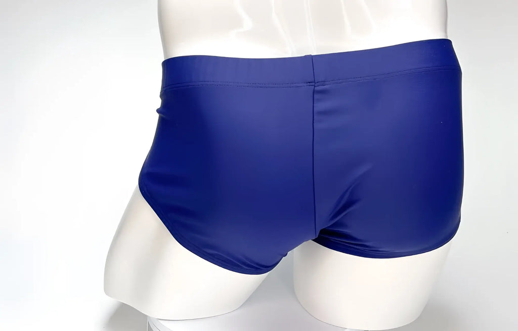 Back view of navy WildmanT swim briefs on a white mannequin, showing a solid-colored, fitted trunk-style design.