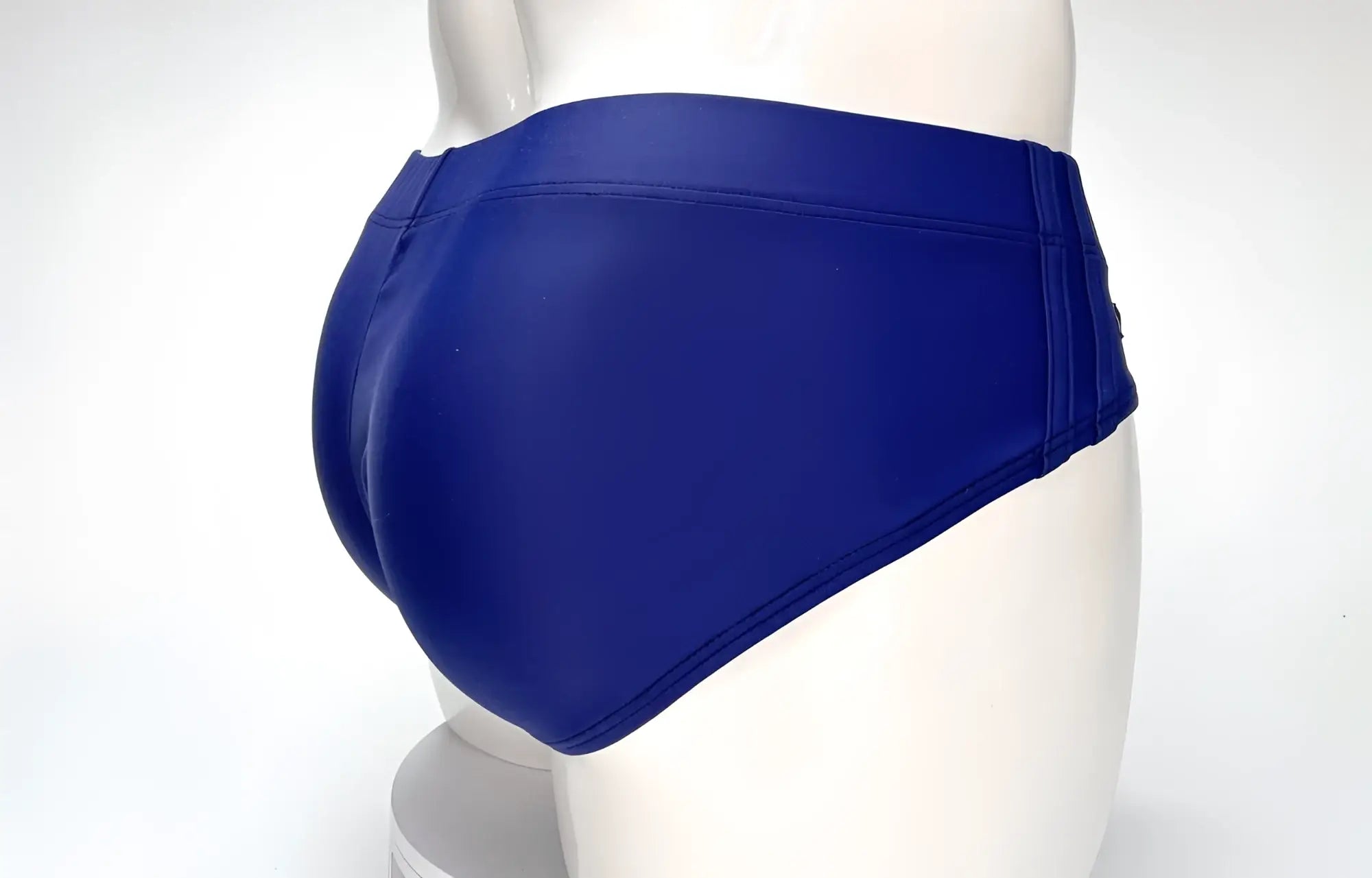 Back view of navy blue WildmanT swim briefs on a white mannequin, showing full-coverage cut and smooth fabric.