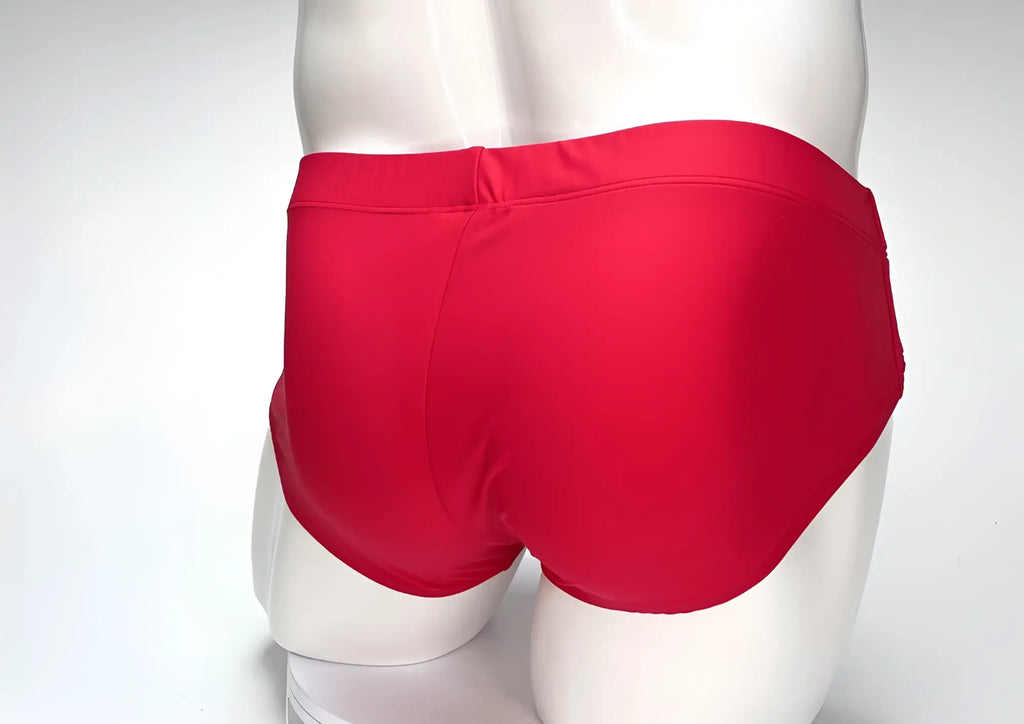 Back view of a solid red WildmanT Big Boy pouch swim brief on a white mannequin torso.