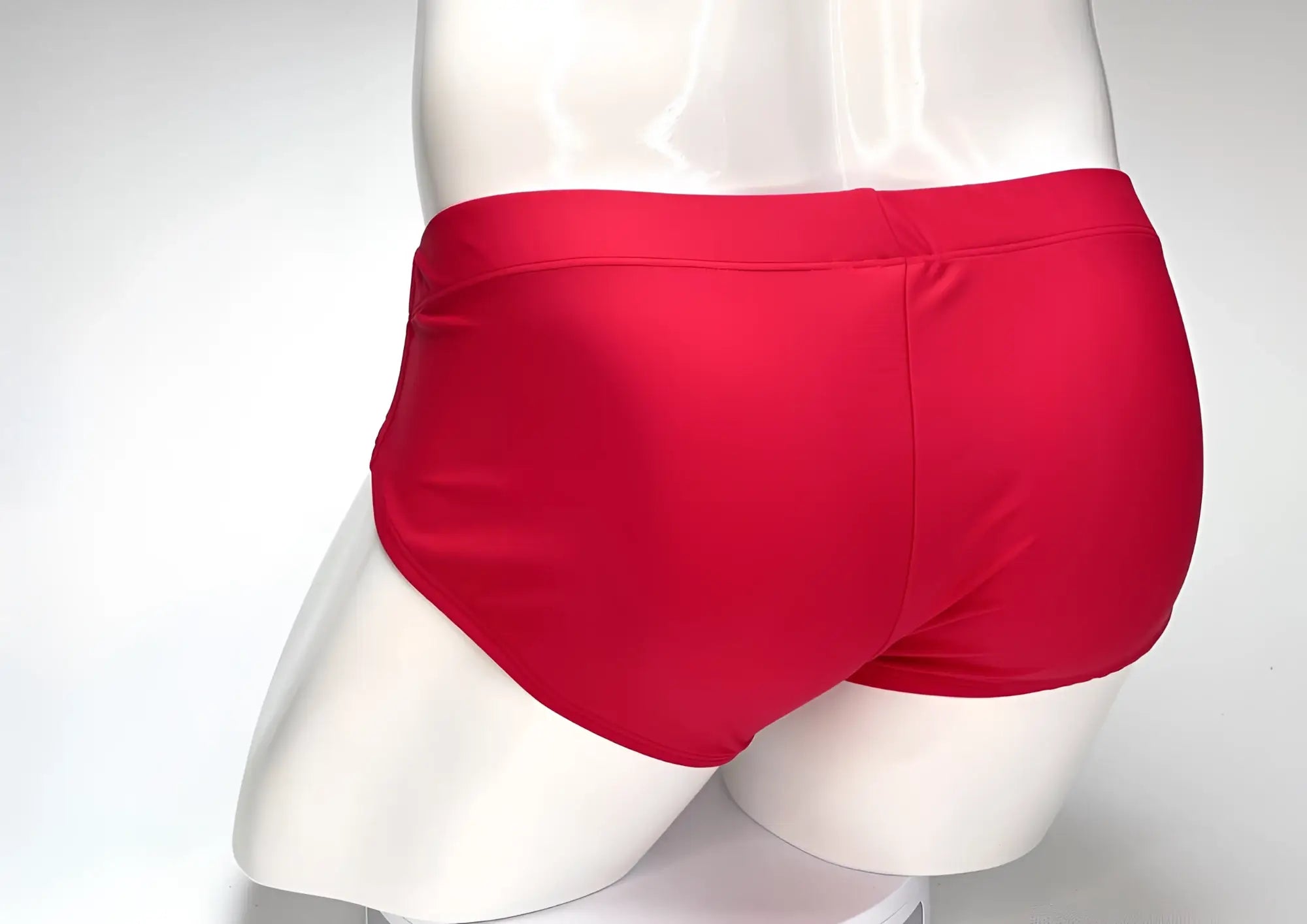 Back view of a plain, red WildmanT Big Boy pouch swim brief on a white mannequin torso.