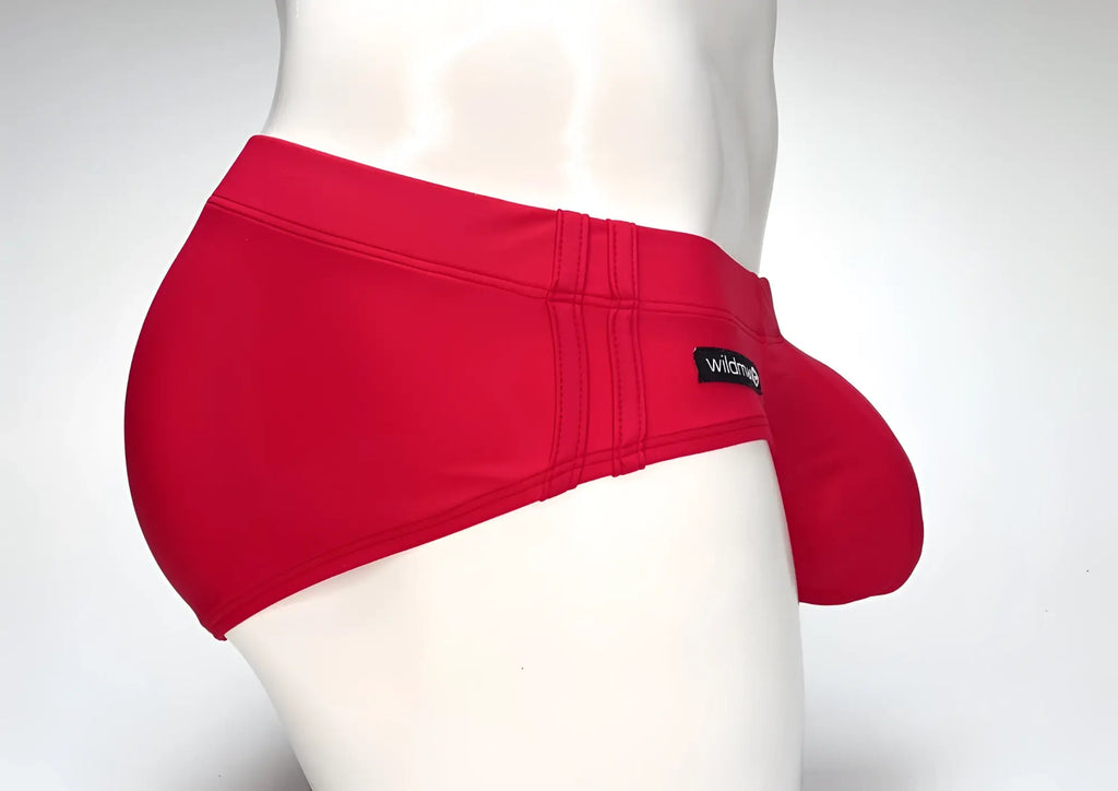 Side profile of a red WildmanT Big Boy pouch swim brief on a mannequin, featuring a prominent front pouch and tag.