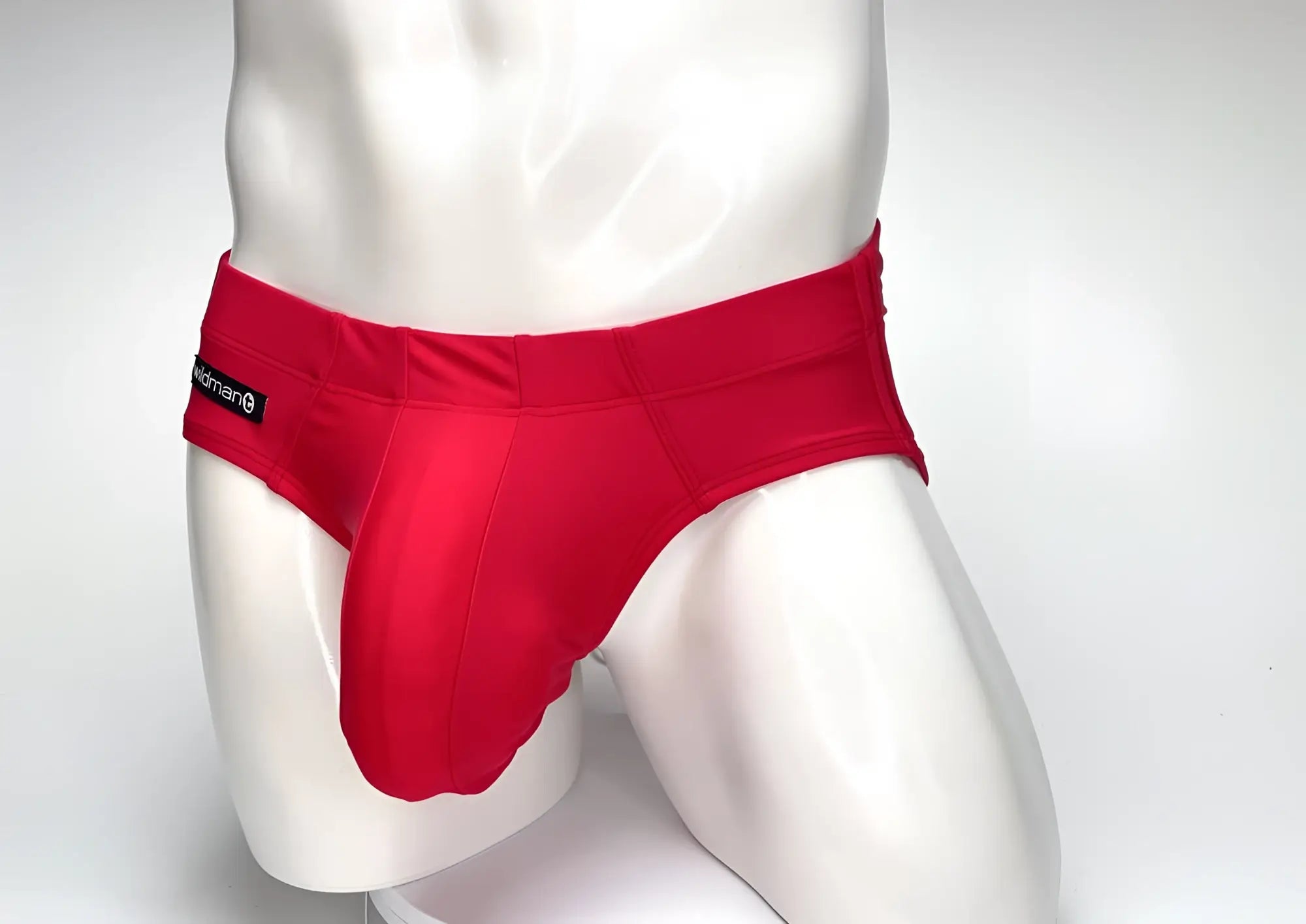 WildmanT Big Boy pouch swim brief in solid red on a mannequin, featuring a prominent front pouch and side logo tab.