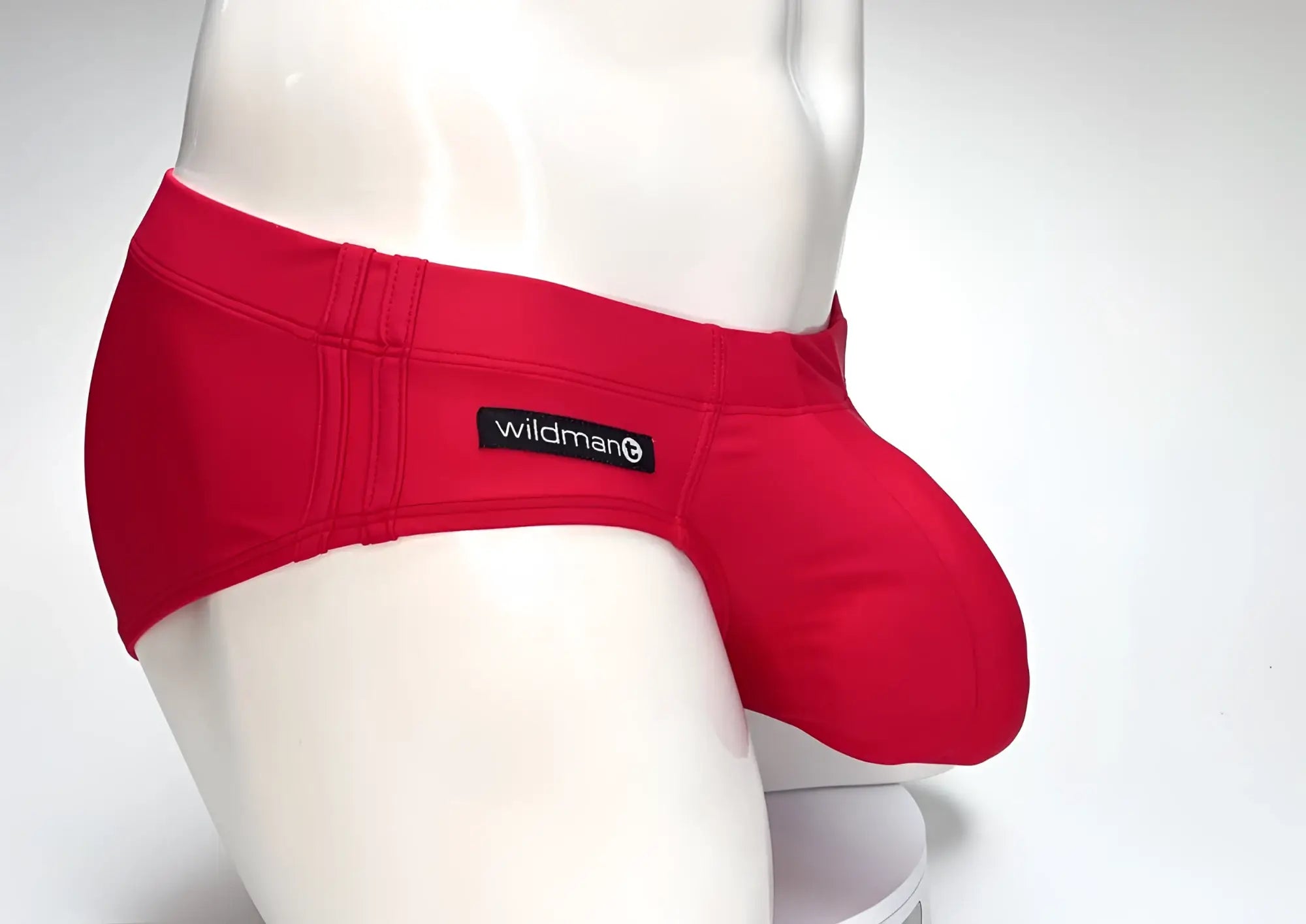 WildmanT red swim brief on a mannequin, featuring a prominent, rounded front pouch and a side-mounted brand tag.