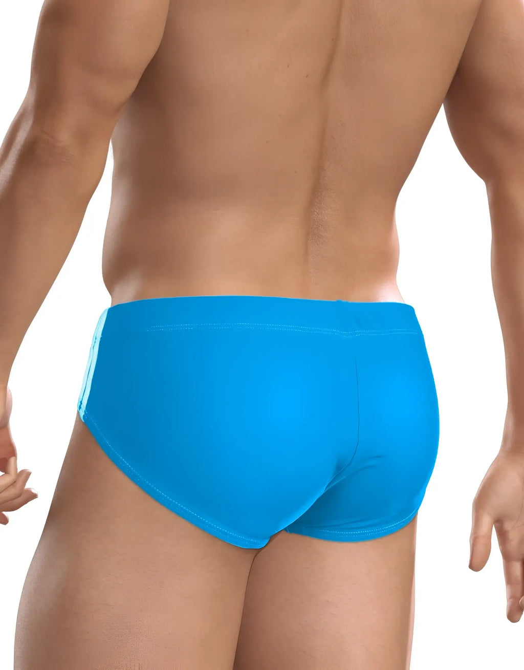 Back view of a muscular man wearing solid teal blue WildmanT Big Boy swim briefs against a white background.