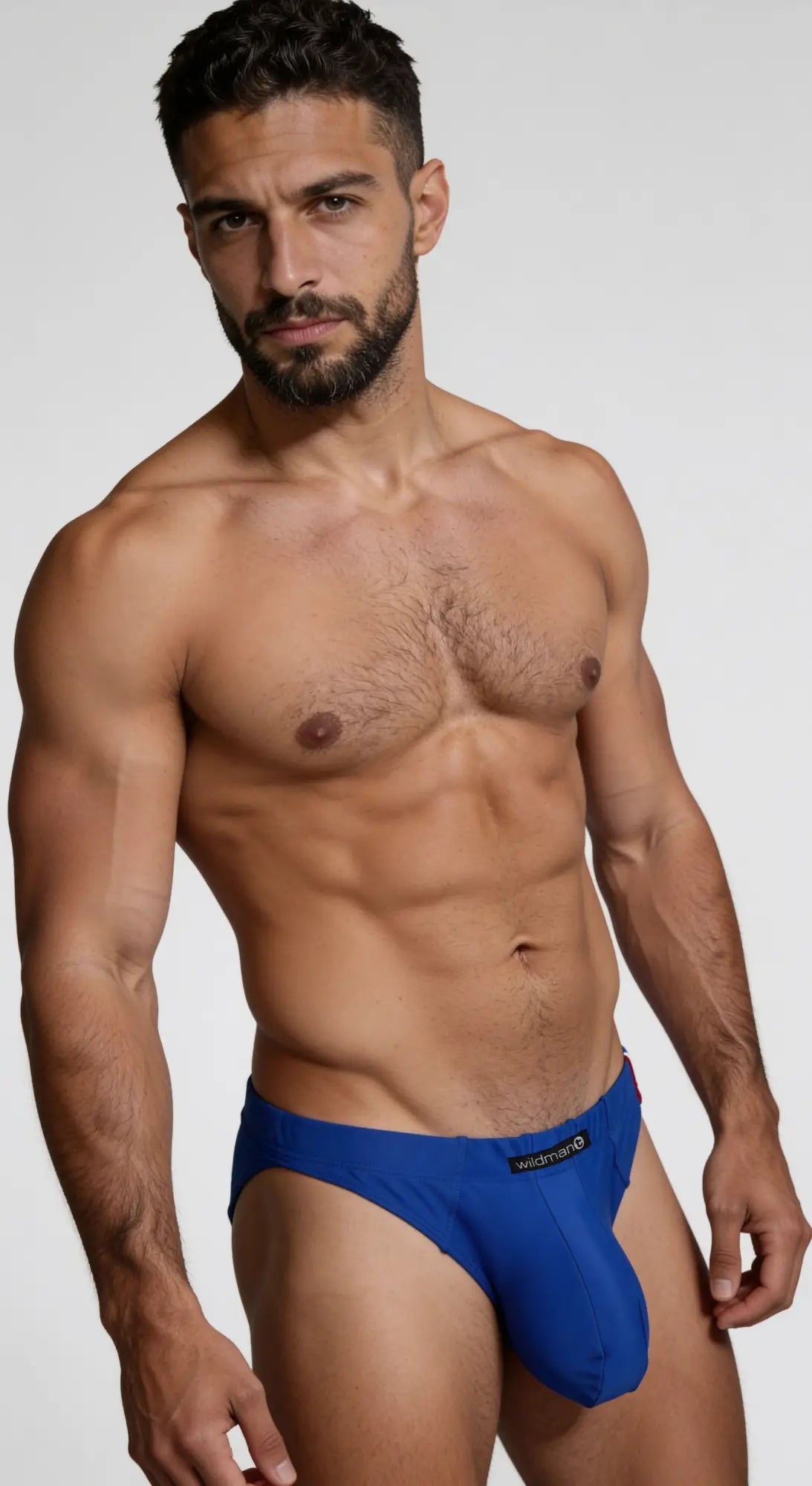 Man wearing a royal blue WildmanT Big Boy pouch swim brief with a prominent contoured front pouch and logo tag.