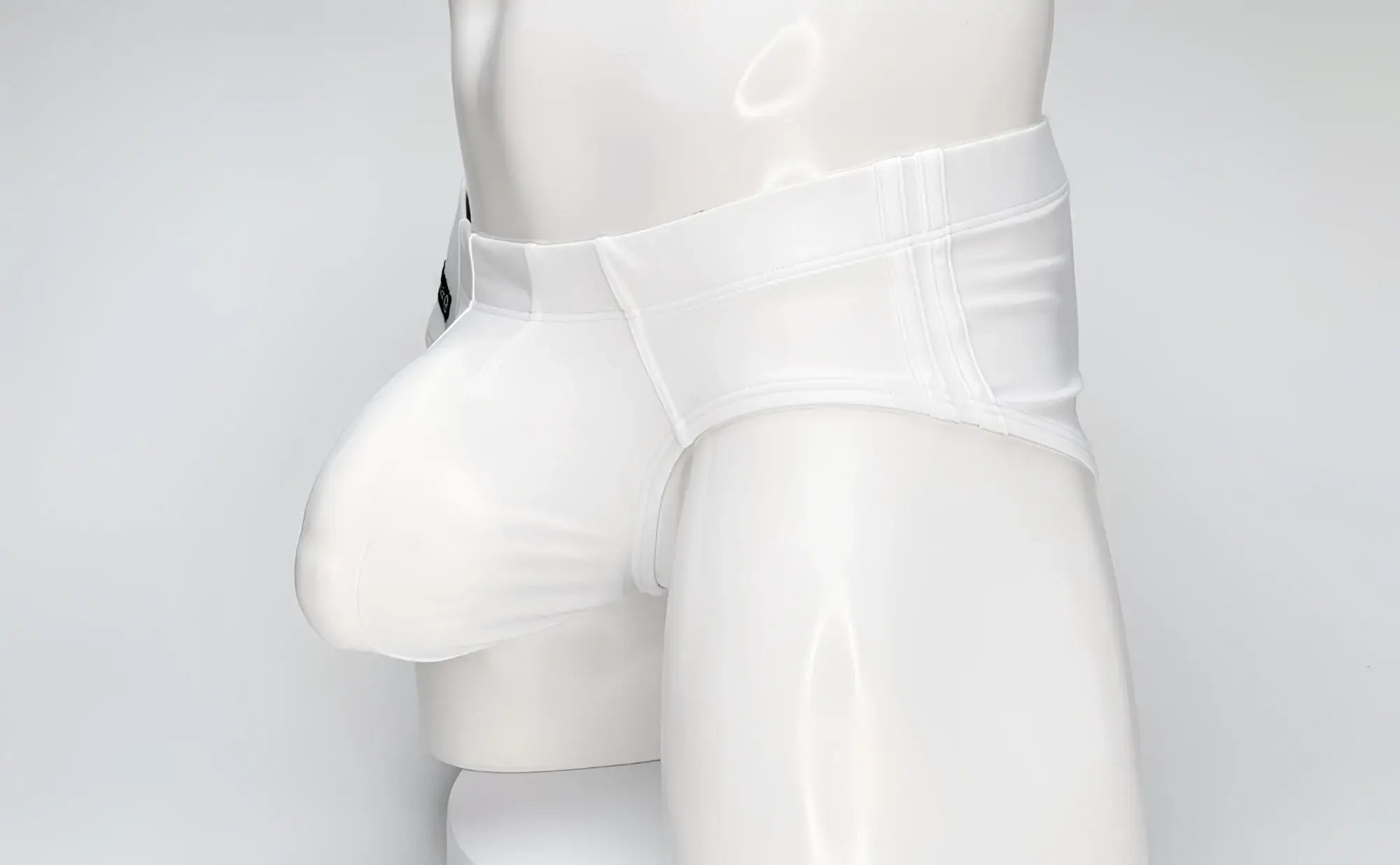 WildmanT white swim brief on a mannequin, featuring a large contoured front pouch and structured waistband.