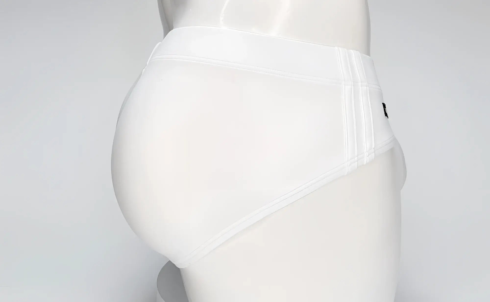 White WildmanT swim brief on a mannequin, featuring a contoured pouch design and side-stitched detailing.