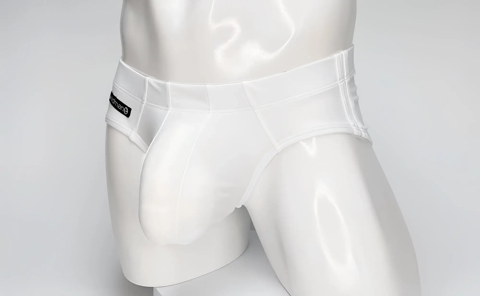 White WildmanT swim brief with a large contoured front pouch, worn by a mannequin, featuring a black side logo tag.