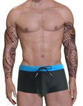 Blue and black square-cut swim trunks with a drawstring waistband and a contour pouch, worn by a man with tattoos.