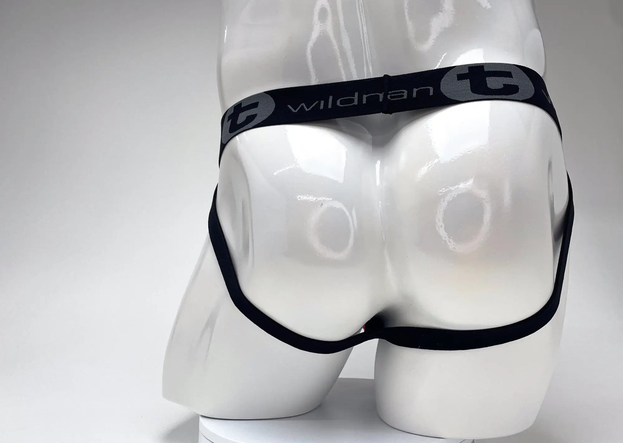 Red and black WildmanT jockstrap on a white mannequin, featuring a branded black elastic waistband.