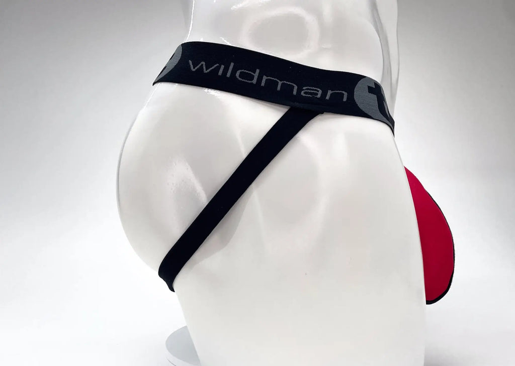 WildmanT red and black jockstrap on a mannequin featuring a wide black branded waistband and a large front pouch.