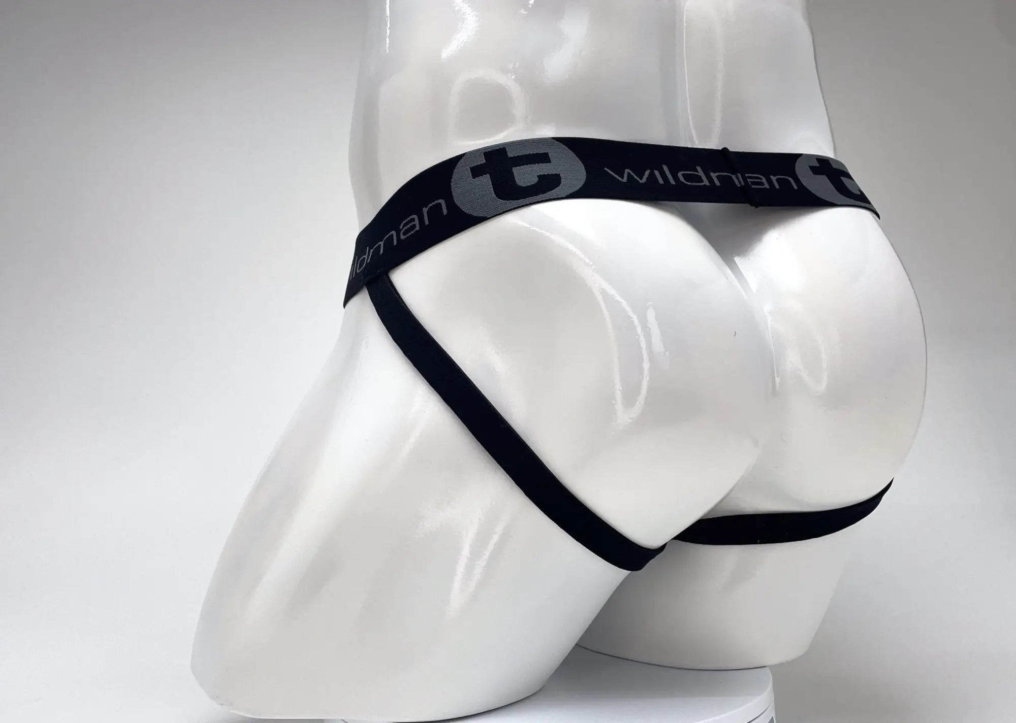 Back view of a WildmanT black and red striped jockstrap on a white mannequin, featuring a branded elastic waistband.
