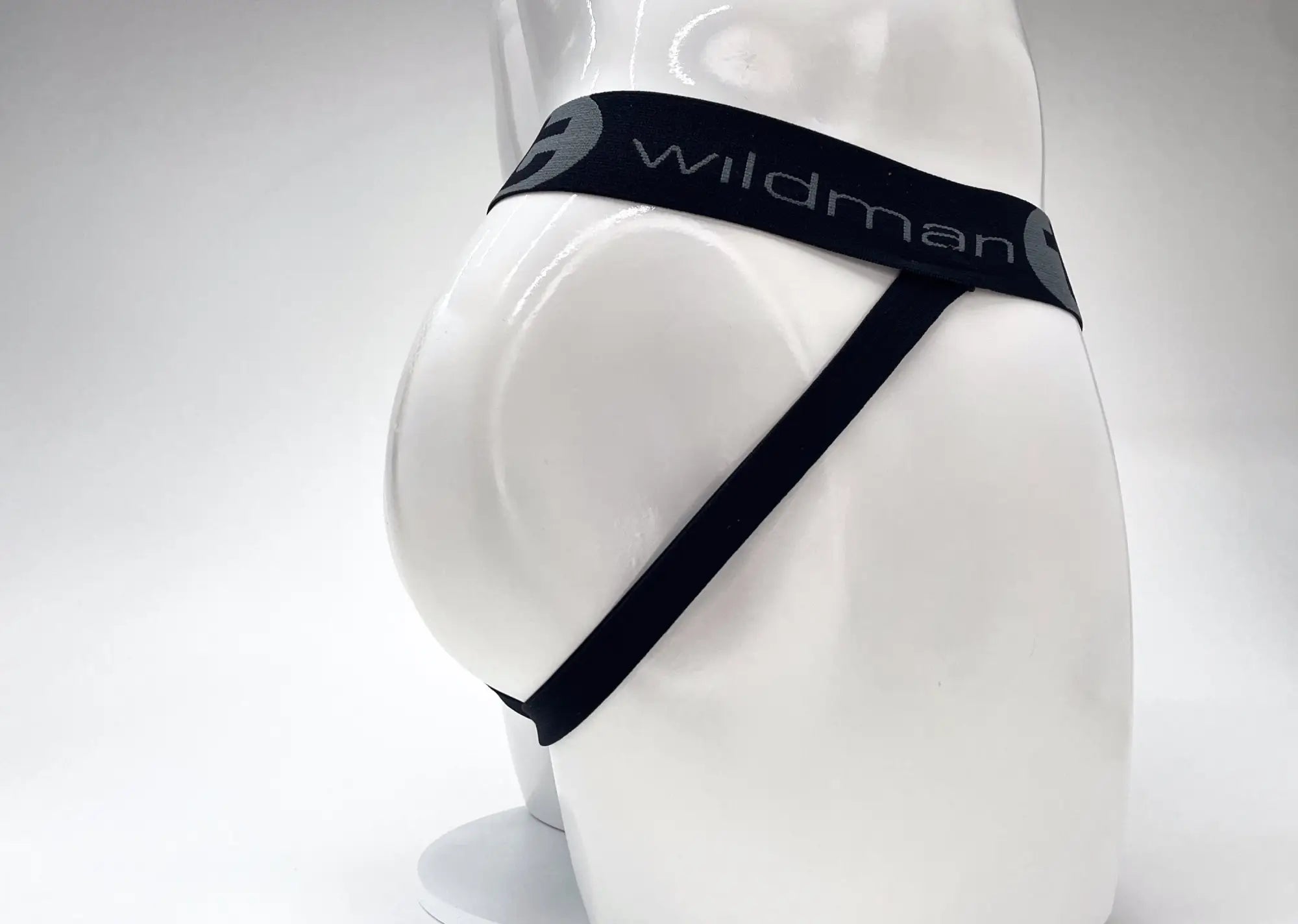 Side view of a red and black jockstrap with a black waistband featuring white "wildman" logo text on a white mannequin.