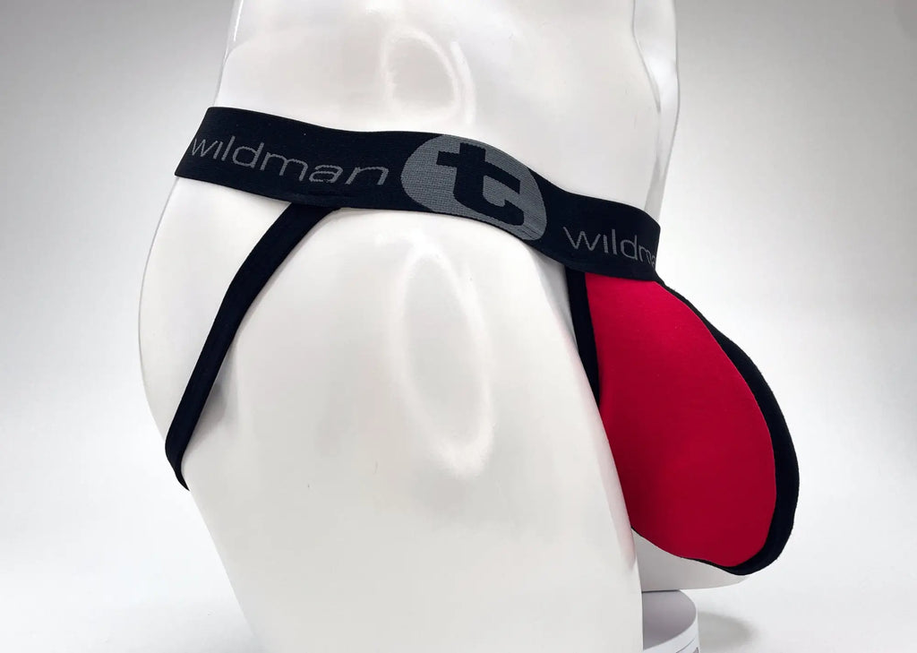 WildmanT red and black jockstrap on a white mannequin, featuring a large pouch and branded black elastic waistband.