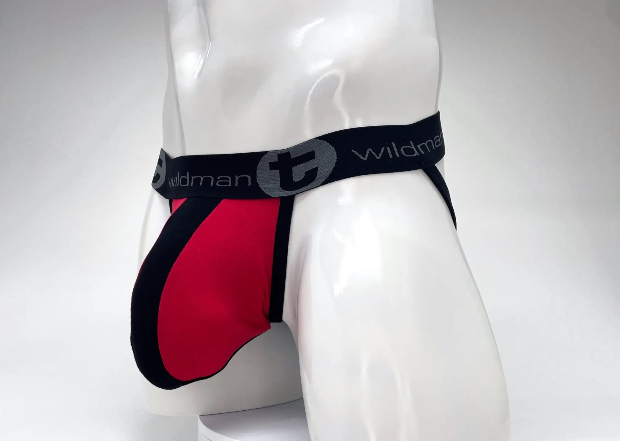 Red and black WildmanT Big Boy pouch jockstrap with a branded elastic waistband on a white mannequin.