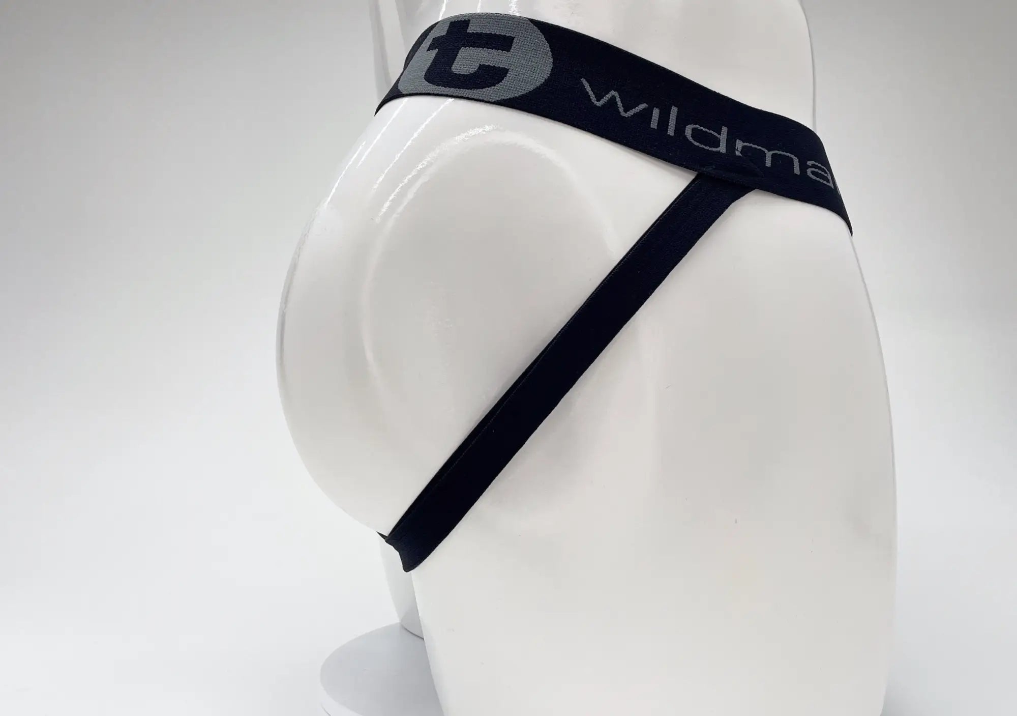 WildmanT jockstrap on a mannequin, featuring a black branded waistband with a grey logo and thin side straps.