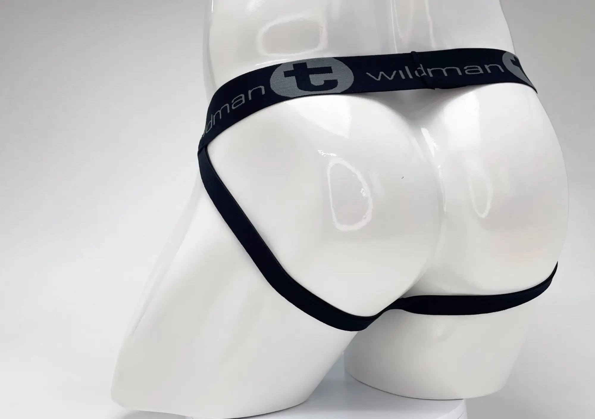 Rear view of a WildmanT jockstrap on a white mannequin, featuring a black branded waistband and leg straps.