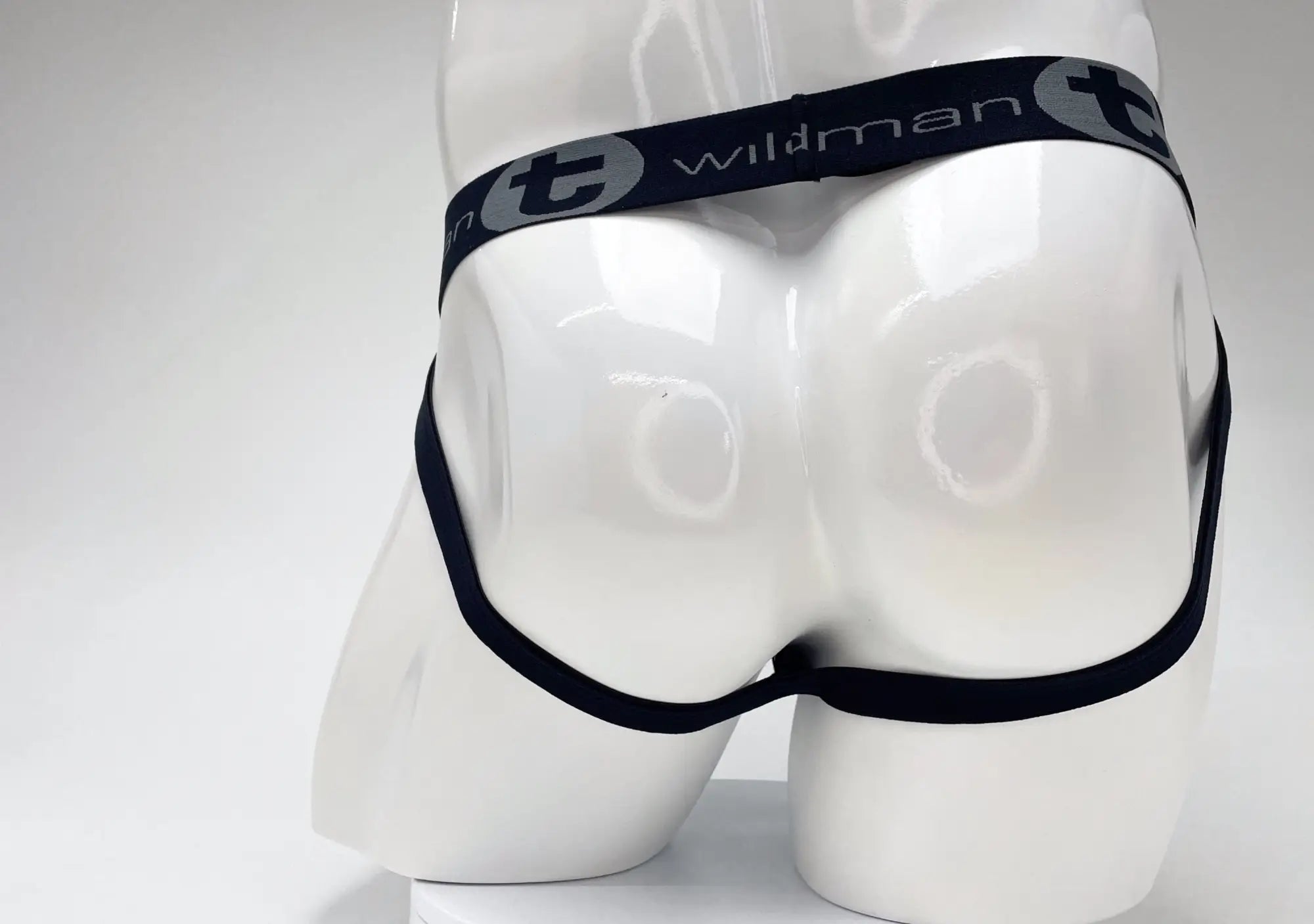 Rear view of a WildmanT jockstrap on a white mannequin featuring a black elastic waistband with grey logo branding.