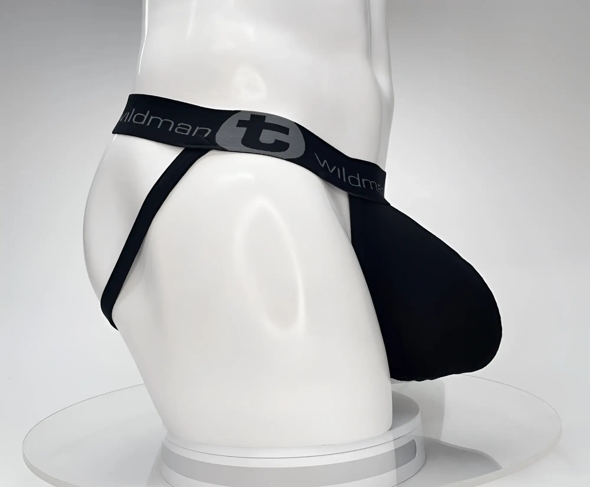 Side view of a black cotton jockstrap with an elastic waistband featuring the grey "WildmanT" logo on a white mannequin.