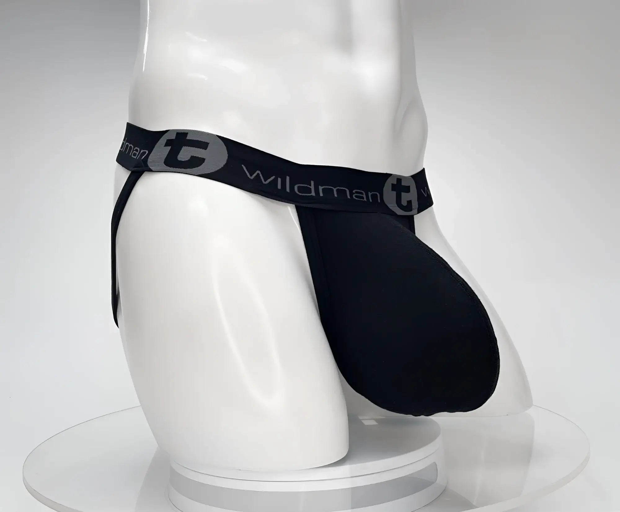 Black WildmanT cotton jockstrap with an oversized pouch and branded elastic waistband on a white mannequin torso.
