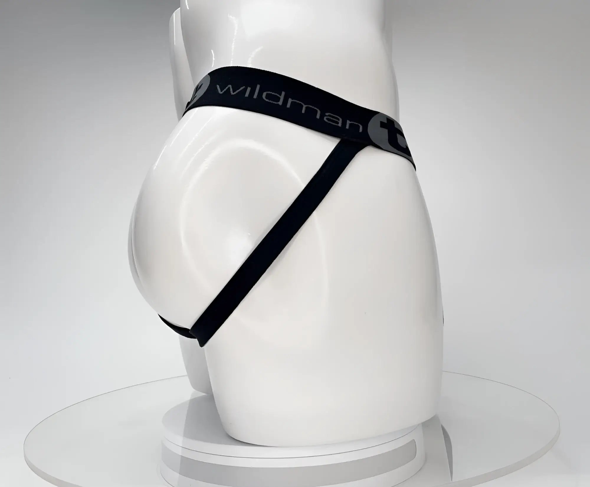 Black WildmanT jockstrap with elastic waistband and brand logo, worn on a white mannequin torso from a side view.