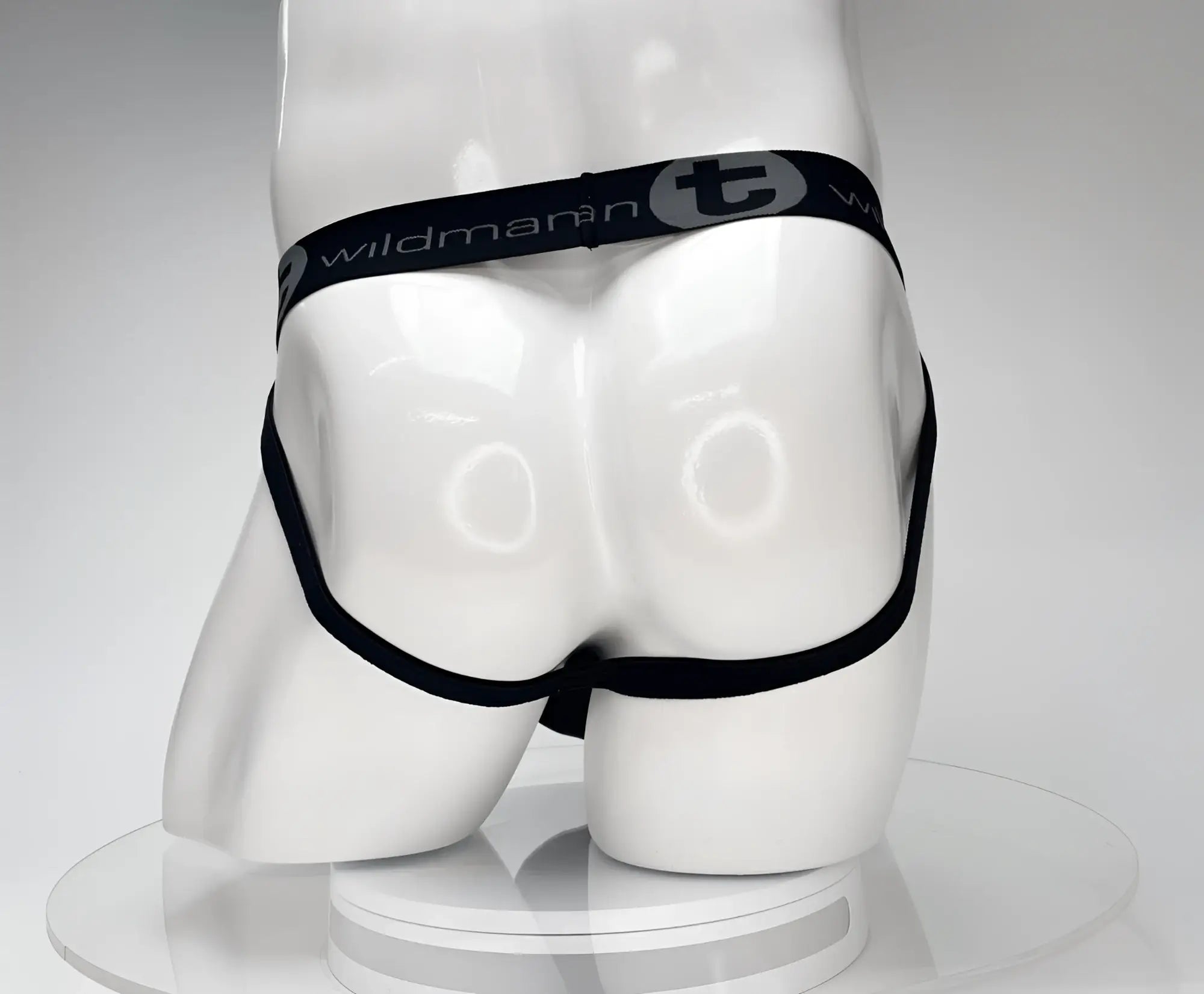 Black WildmanT jockstrap with a branded elastic waistband on a white mannequin torso.