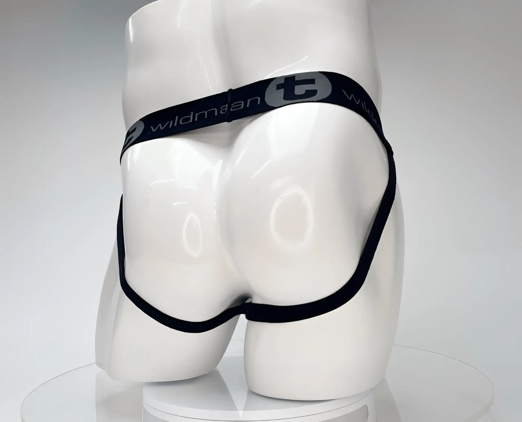 White jockstrap on a mannequin, featuring a black waistband with WildmanT logo and thin black leg straps.