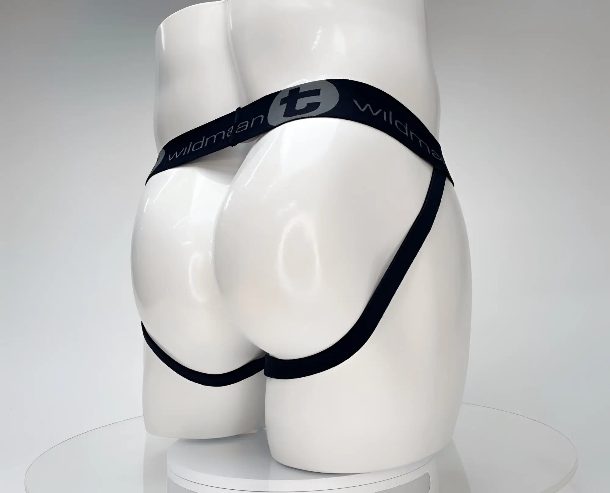 White WildmanT jockstrap on a mannequin, featuring a black branded waistband and leg straps.