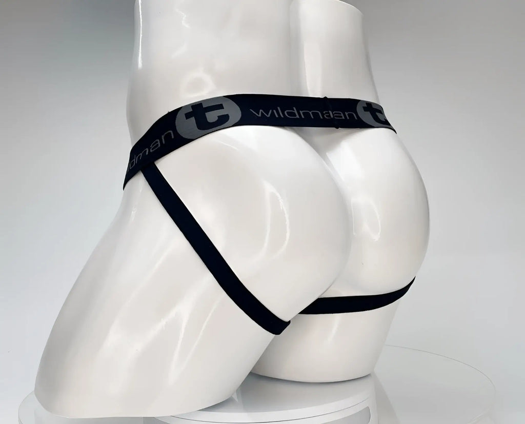 White jockstrap on a mannequin, featuring a black waistband with "WildmanT" branding and thin black leg straps.